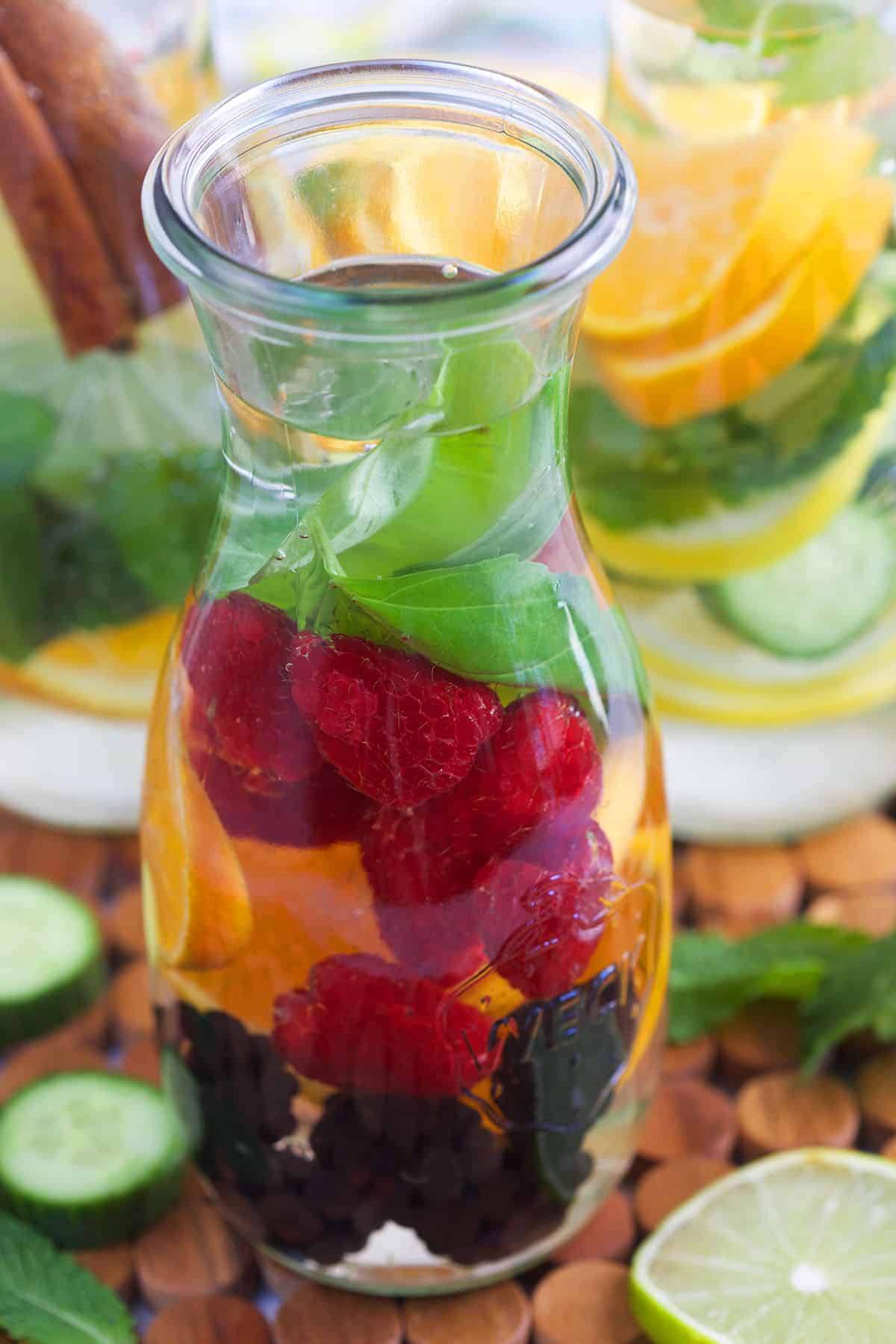 Infused water in a glass bottle with berries, basil and oranges. 