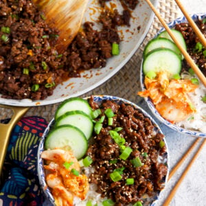 Two bowls of Korean ground beef and veggies are placed next to a skillet.