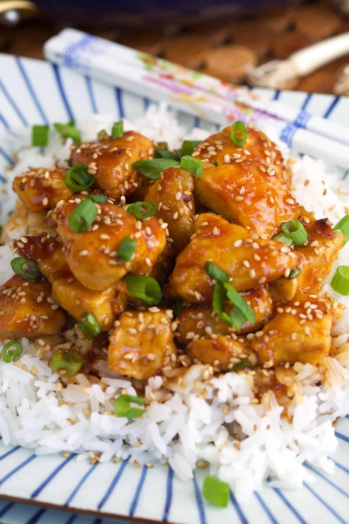 A serving of sesame chicken is placed over white rice.