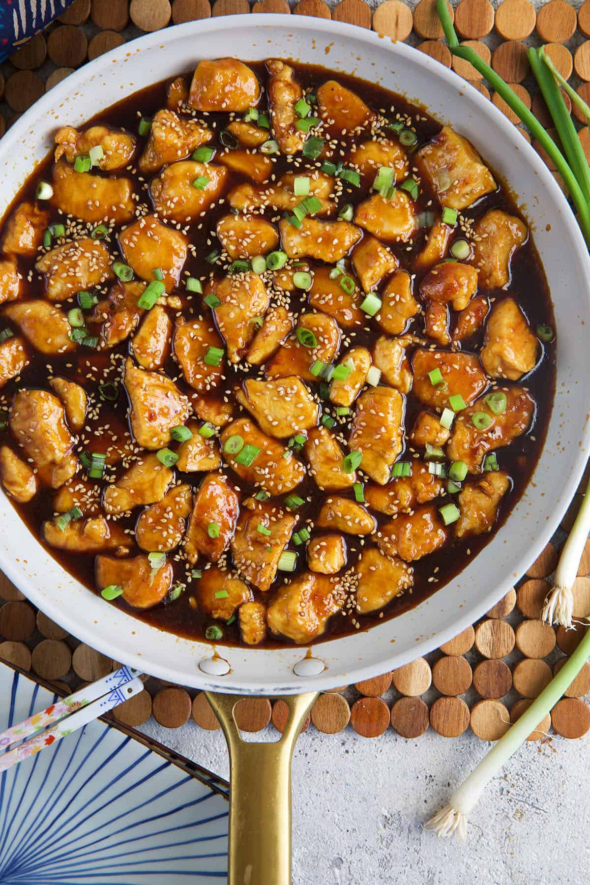 A skillet is filled with sesame chicken. 
