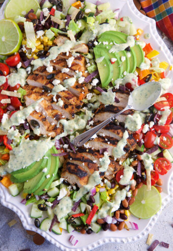 A fully assembled southwest chicken salad is topped with dressing.