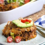 A serving of taco casserole is plated on a round white plate.