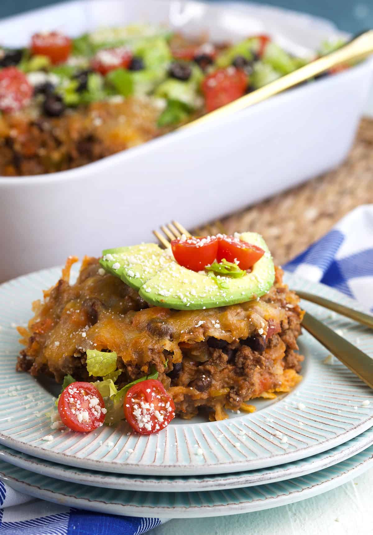 A serving of taco casserole is plated on a round white plate. 