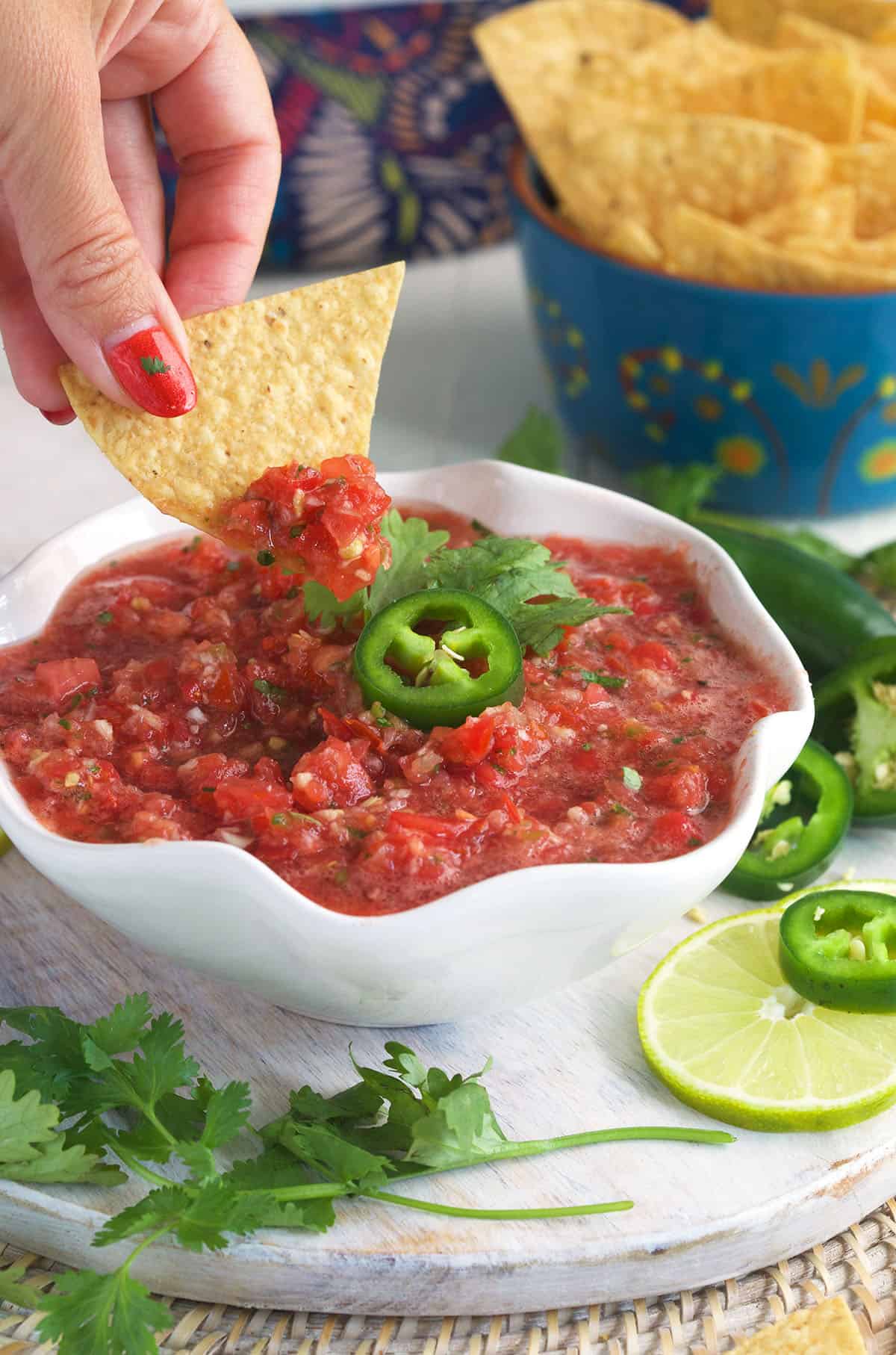 A chip is being dipped into Mexican salsa. 