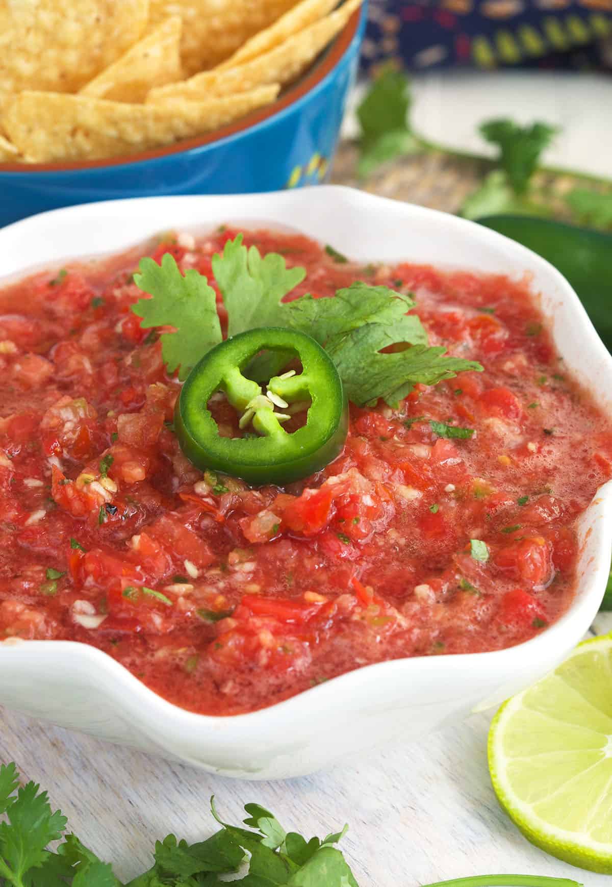 Cilantro and fresh jalapeños garnish a small bowl of salsa. 
