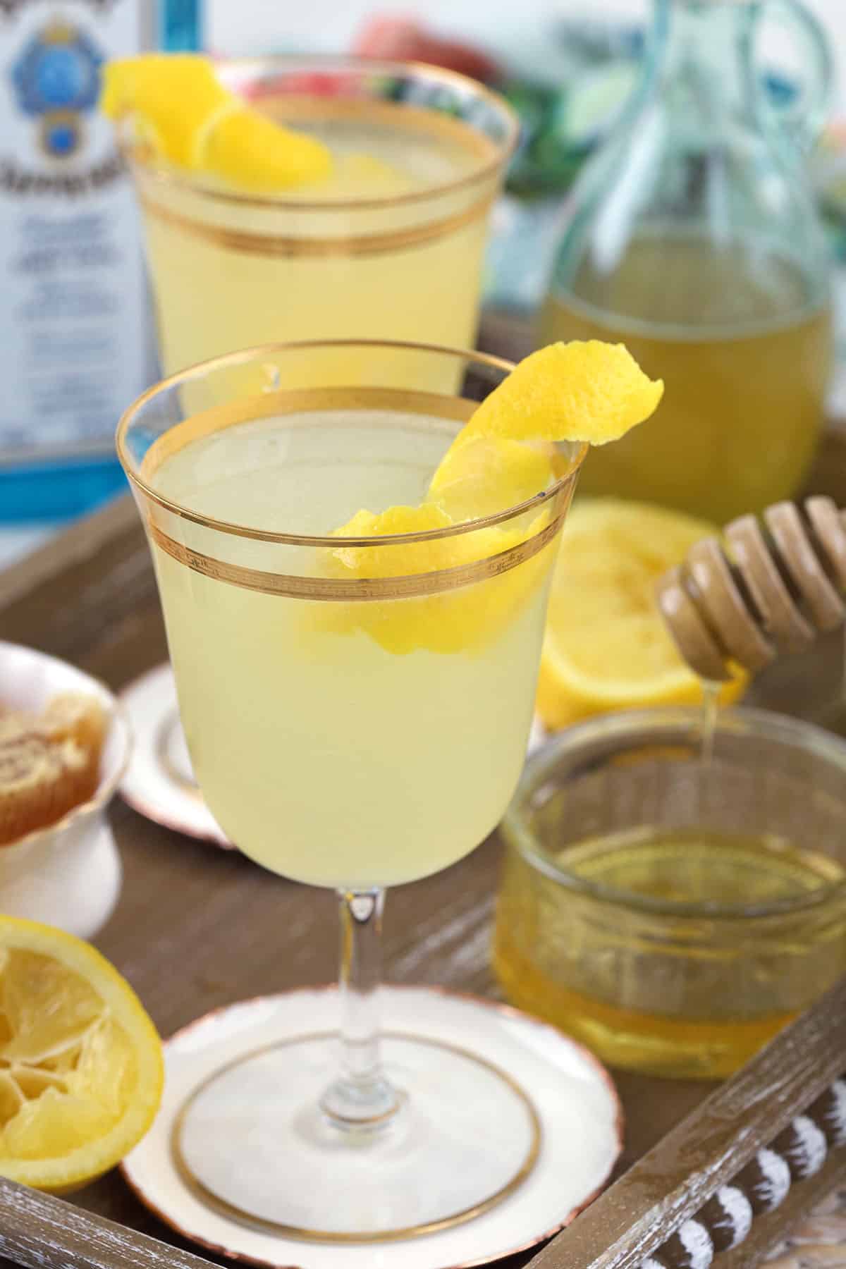 A bees knees cocktail is garnished with a lemon twist. 