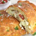 A sliced calzone is garnished with fresh herbs.