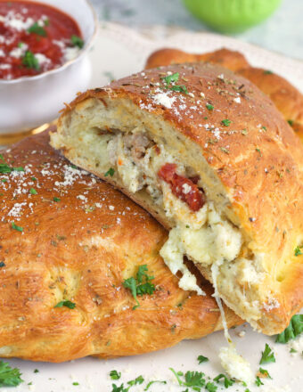 A sliced calzone is garnished with fresh herbs.