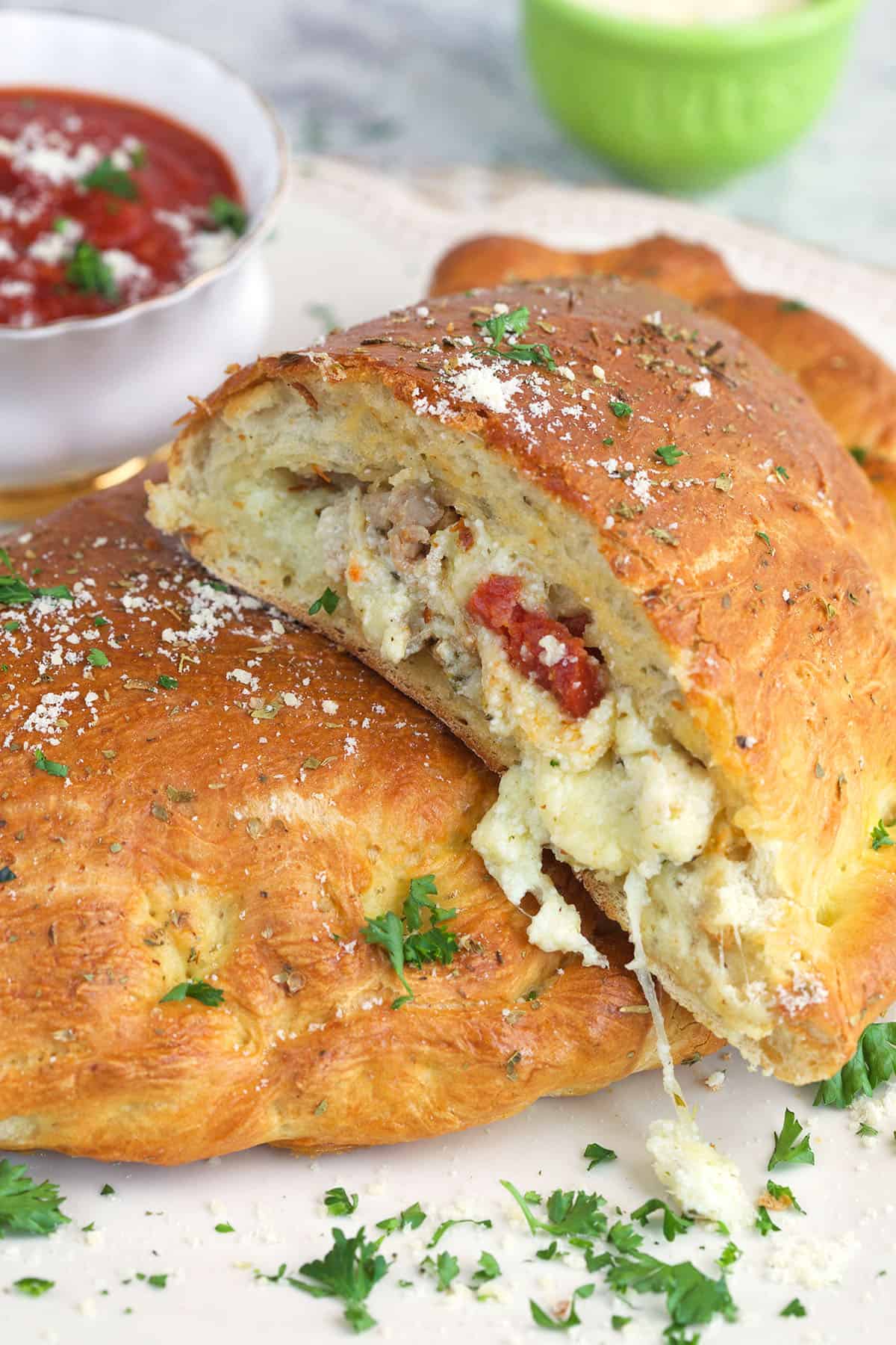 A sliced calzone is garnished with fresh herbs. 