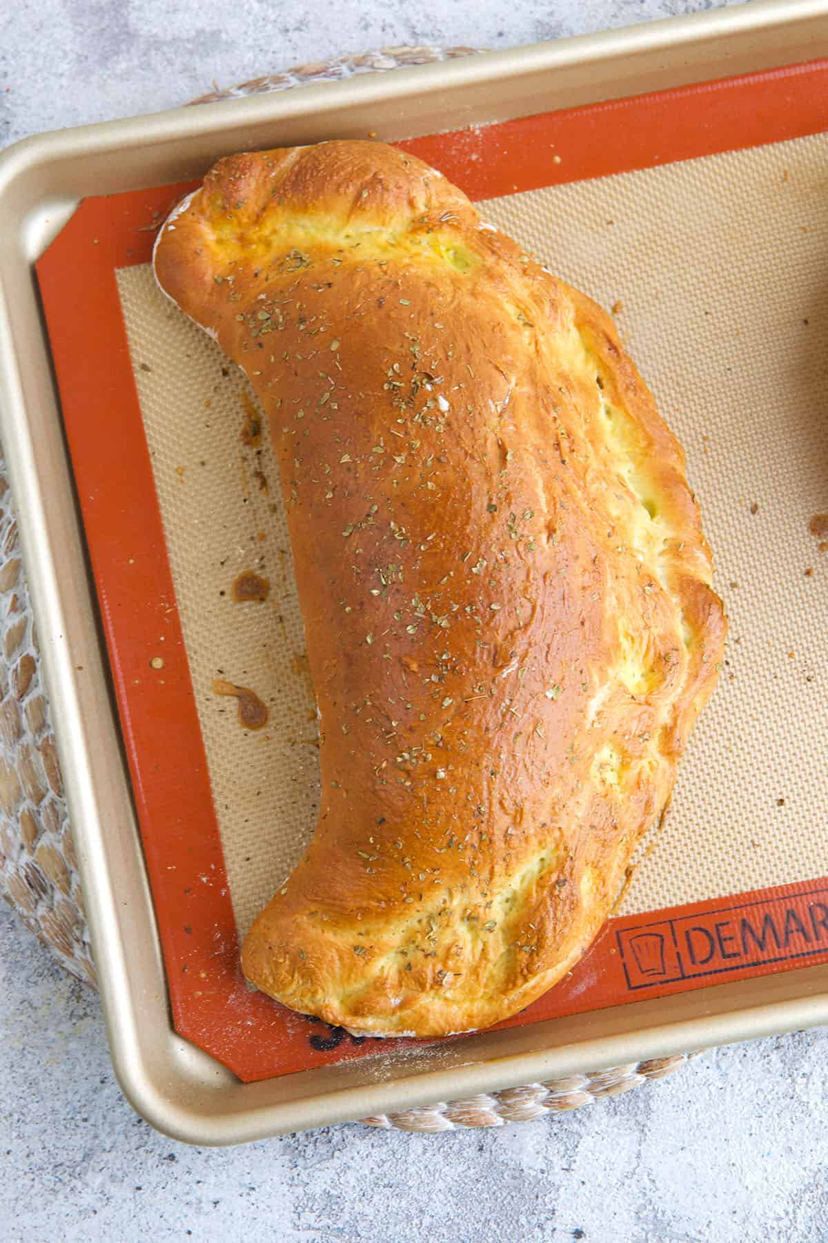 A baked calzone is on a baking sheet. 