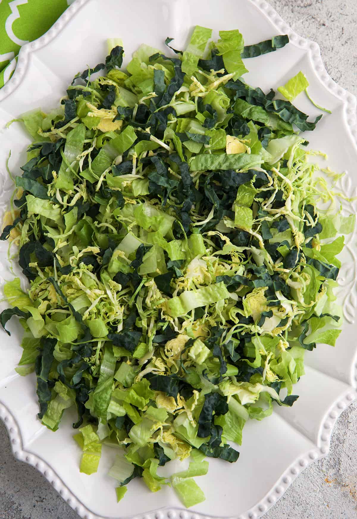 A white platter is topped with fresh greens. 