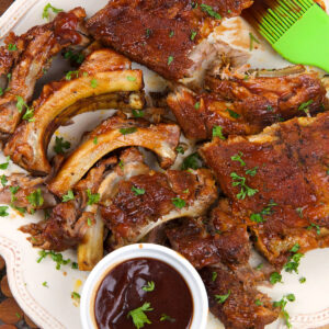 Crockpot ribs are spread out on a white platter.