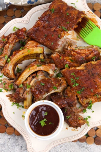 Crockpot ribs are spread out on a white platter.