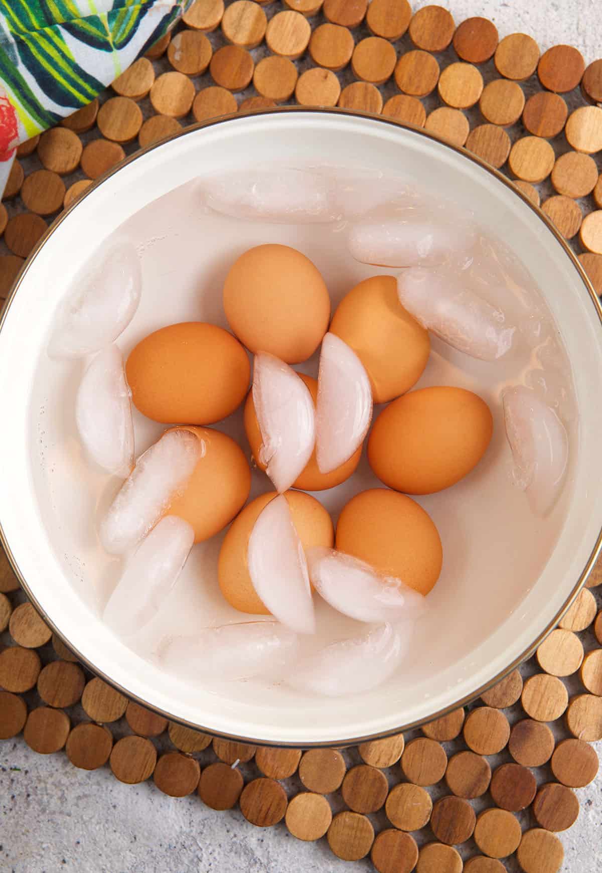 Hard boiled eggs are placed in a bowl of ice water. 