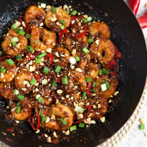 Kung pao shrimp is cooking in a skillet.