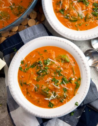 A white bowl is filled with tomato florentine soup.