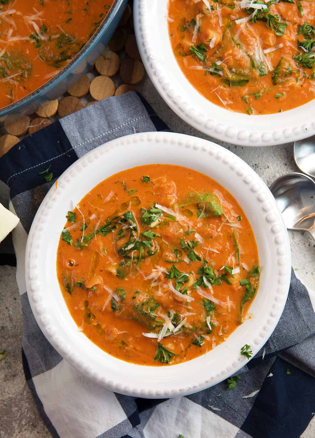 A white bowl is filled with tomato florentine soup. 