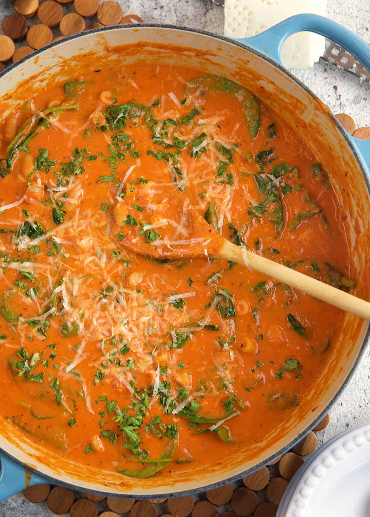 A large dutch oven is filled with tomato florentine soup. 