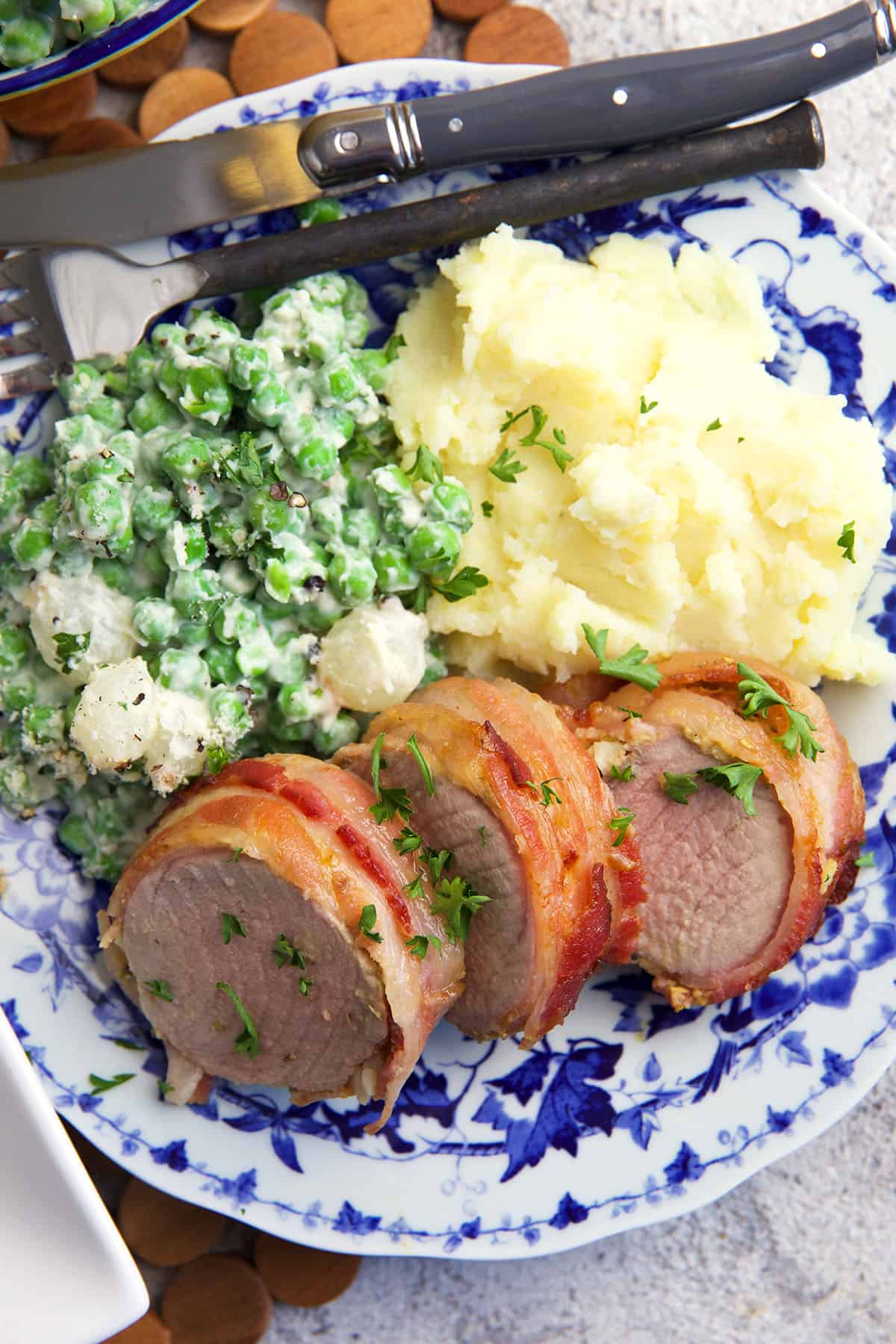 Pork tenderloin is served with creamed peas and mashed potatoes. 