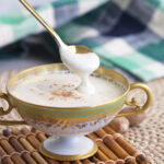 A spoon is drizzling sauce back into a bowl.