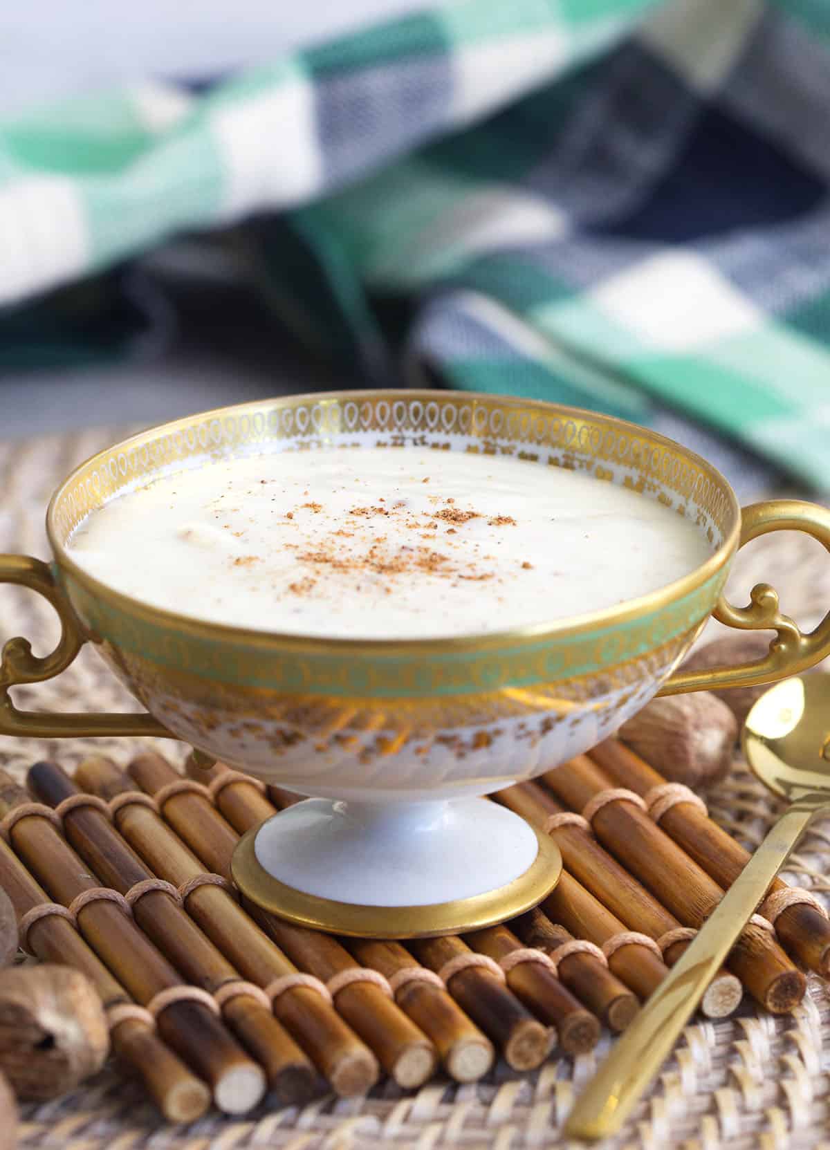 A golden spoon is placed next to a small bowl of bechamel sauce. 