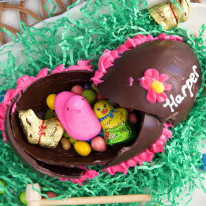 A little wooden mallet is placed beside a broken chocolate Easter egg.