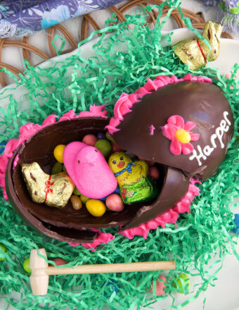 A little wooden mallet is placed beside a broken chocolate Easter egg.