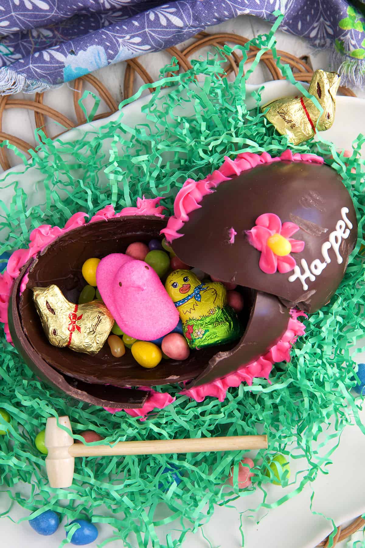 A little wooden mallet is placed beside a broken chocolate Easter egg. 
