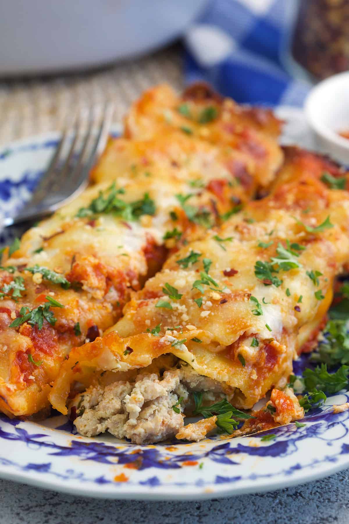 A serving of chicken cannelloni is placed on a blue and white plate. 