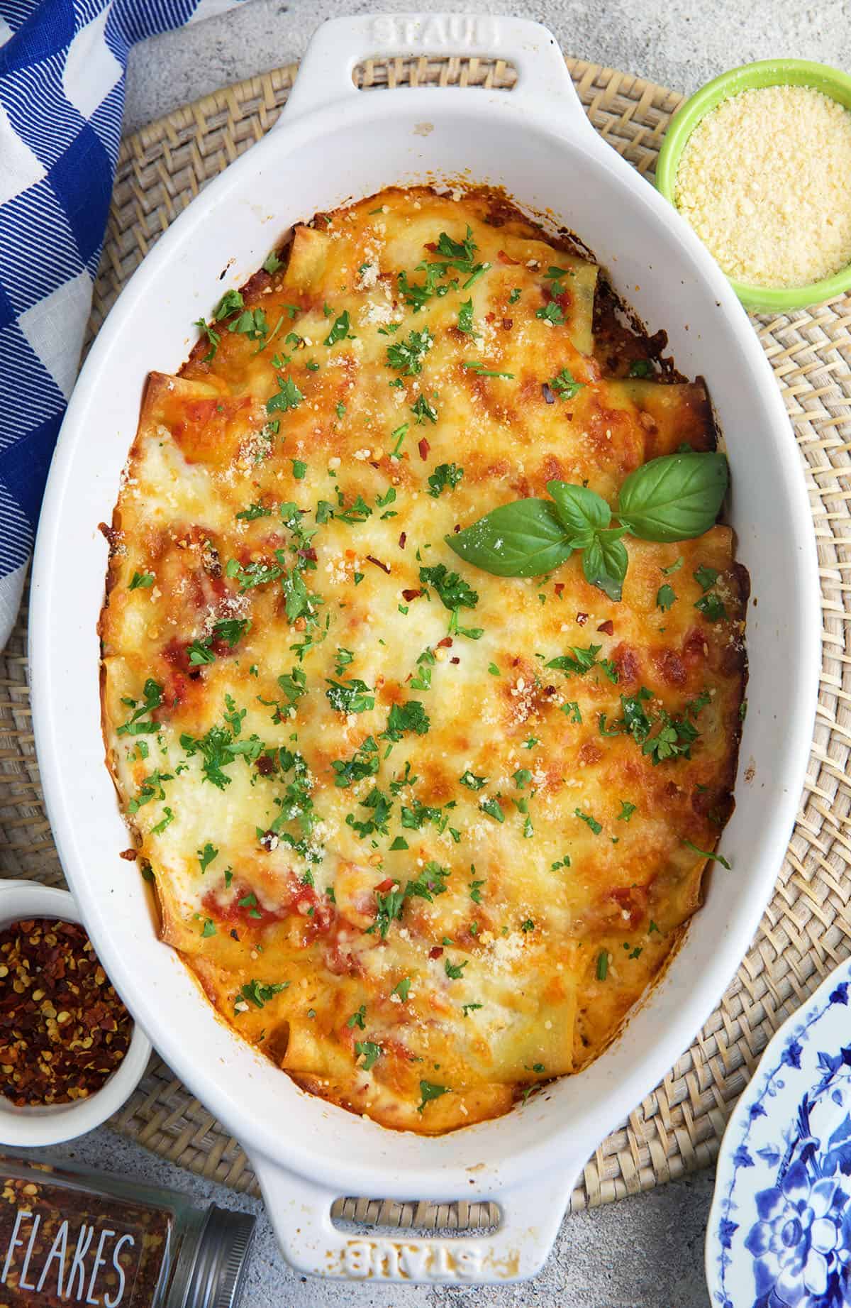 A white baking dish is filled with cooked spinach chicken cannelloni. 