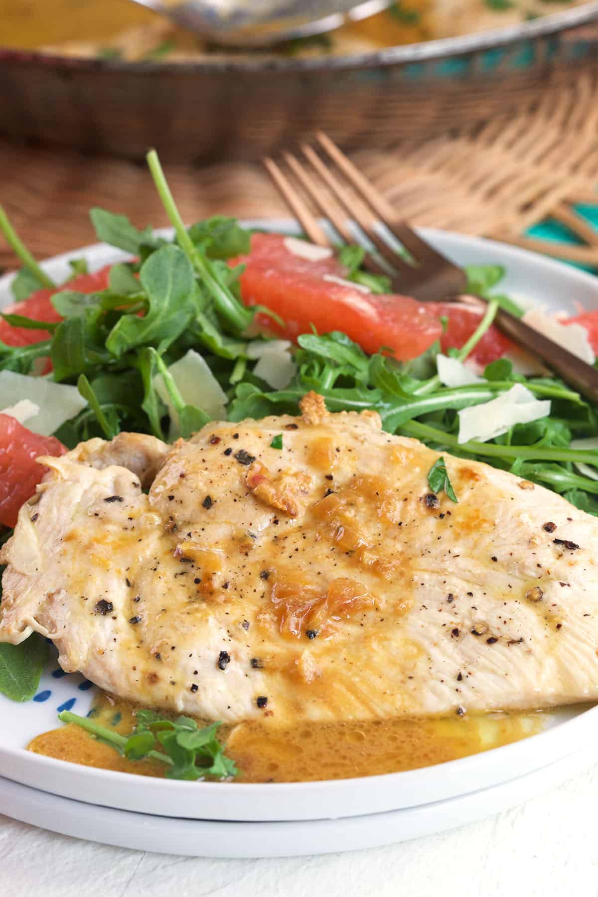 Chicken paillard and salad is on a white plate. 