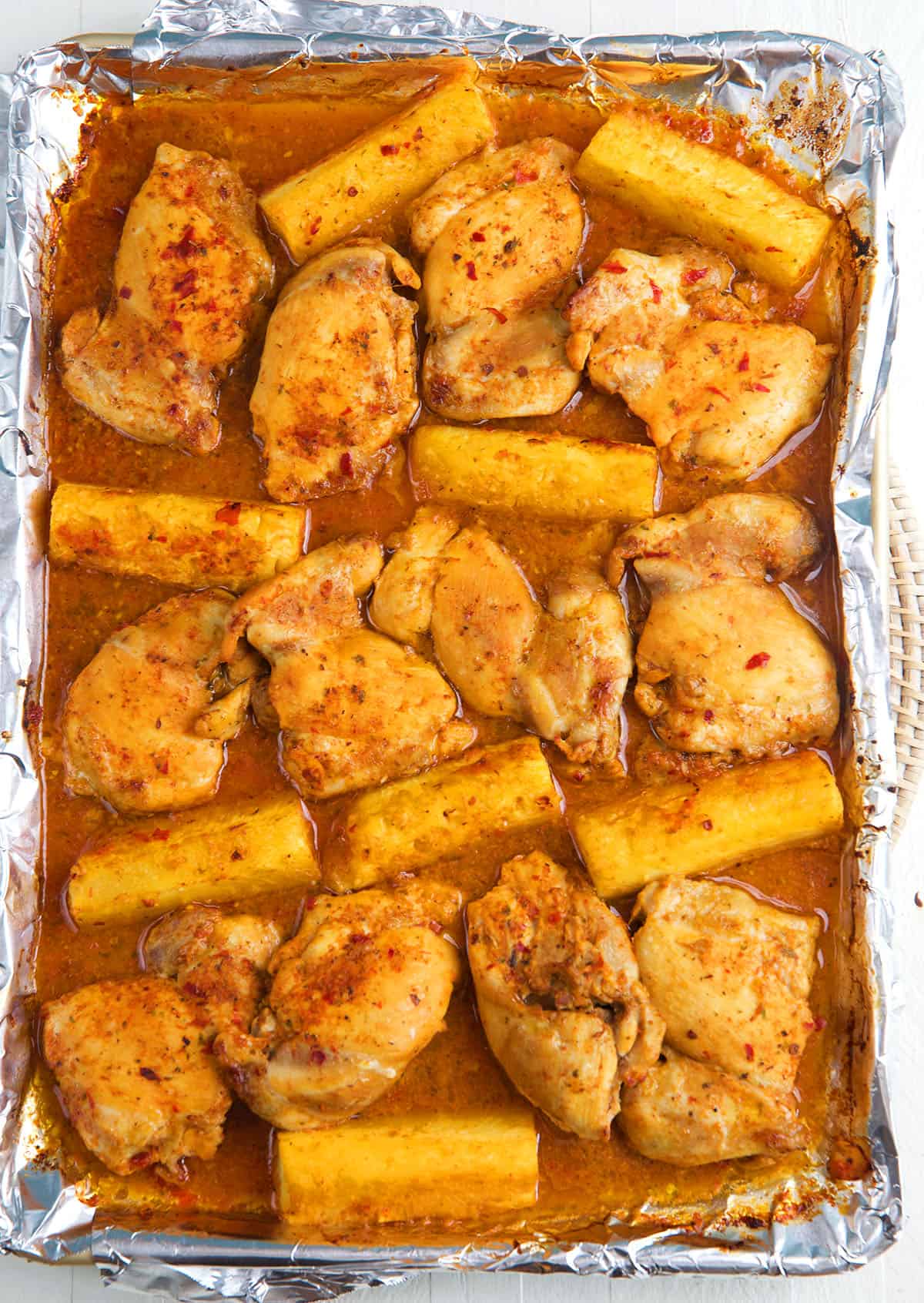 Chicken and pineapple are spread out on a baking sheet. 