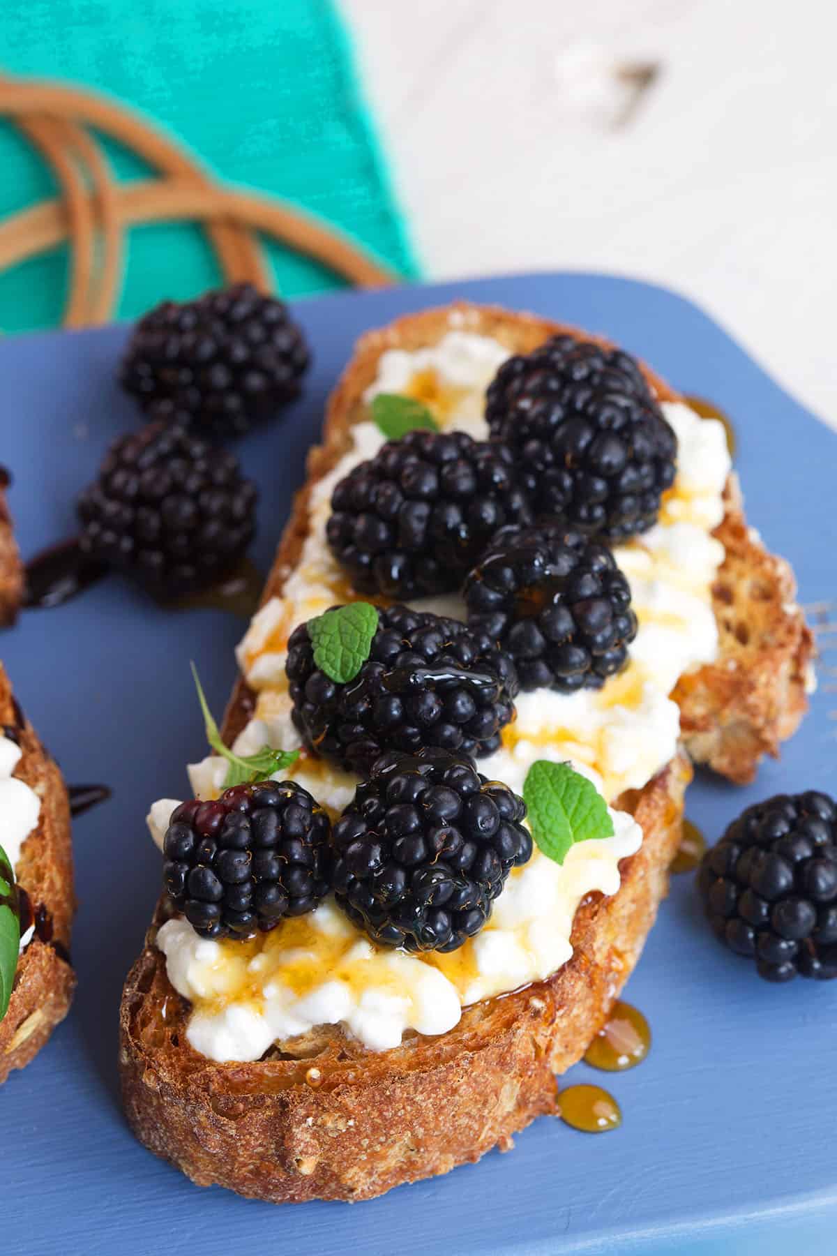 Blackberries are placed on top of a piece of cottage cheese toast.