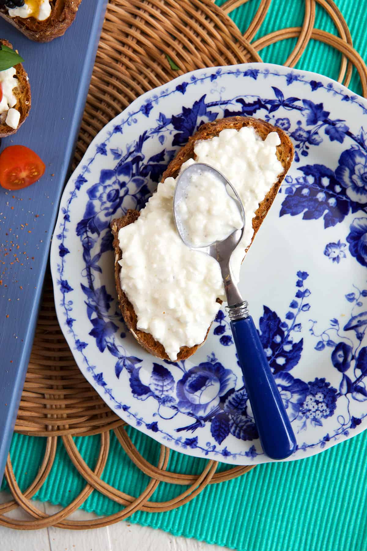 Cottage cheese is being smeared on a piece of toast.