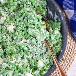 A large spoon is placed in a skillet of creamed peas.