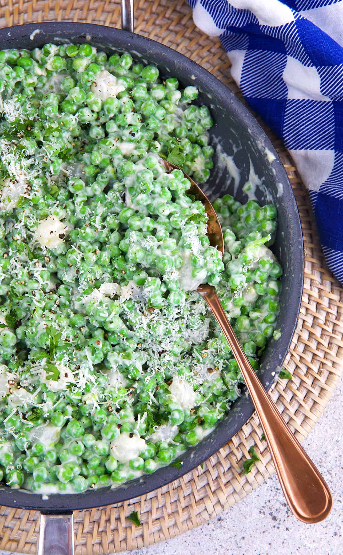 A large spoon is placed in a skillet of creamed peas. 