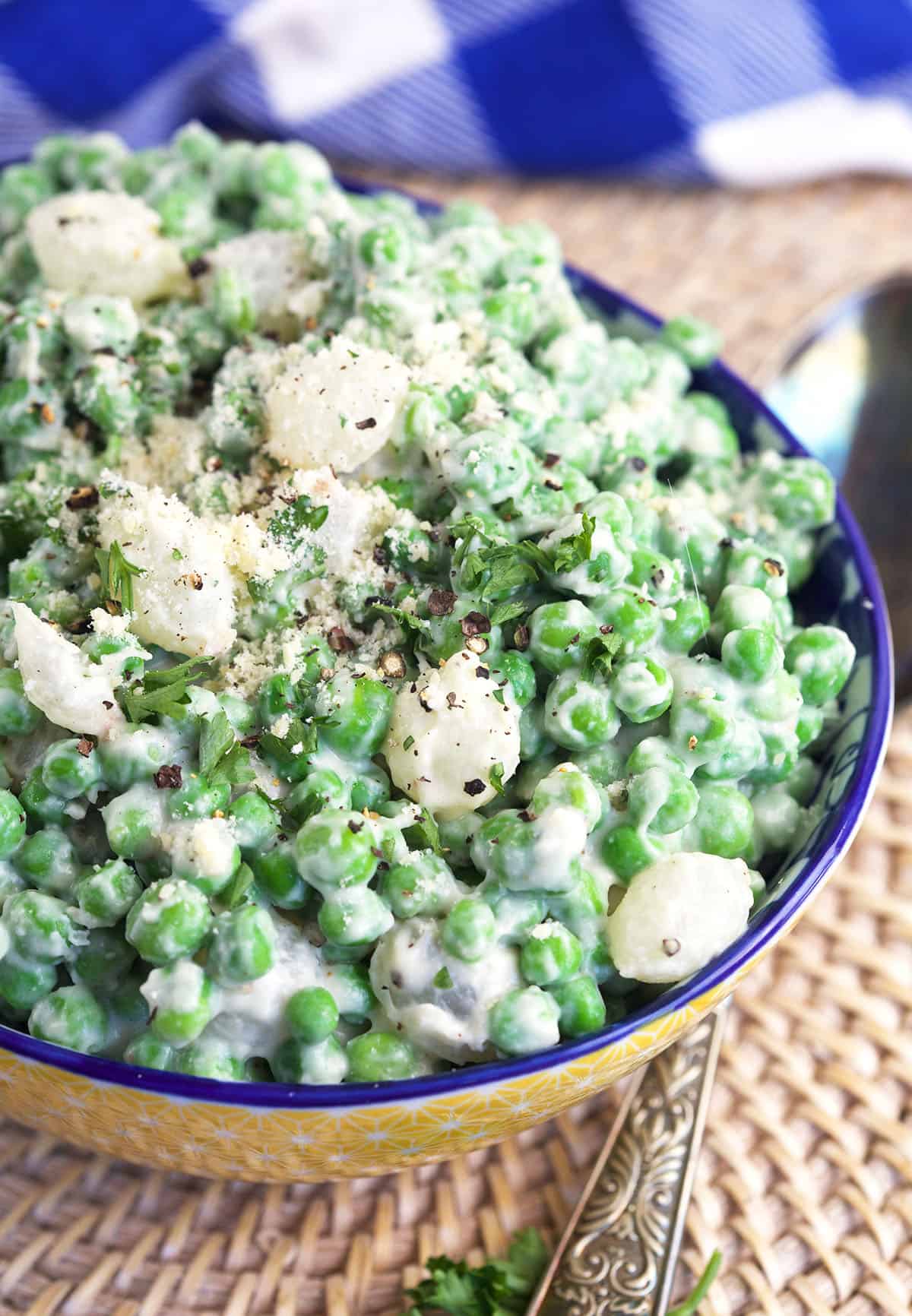 Cracked black pepper is sprinkled on a bowl of creamed peas. 