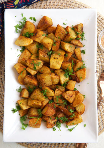 A rectangular serving plate is topped with crispy breakfast potatoes.