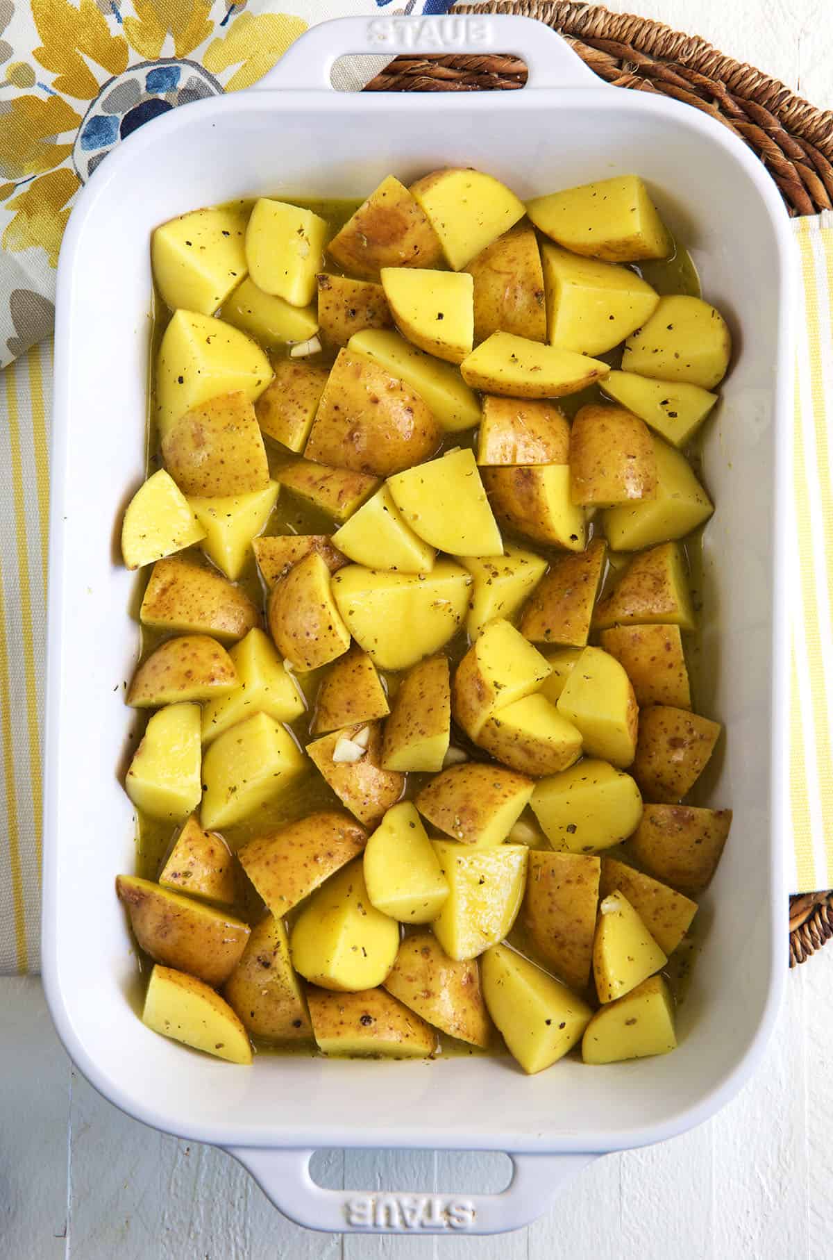 A white baking dish is filled with Greek lemon potatoes. 
