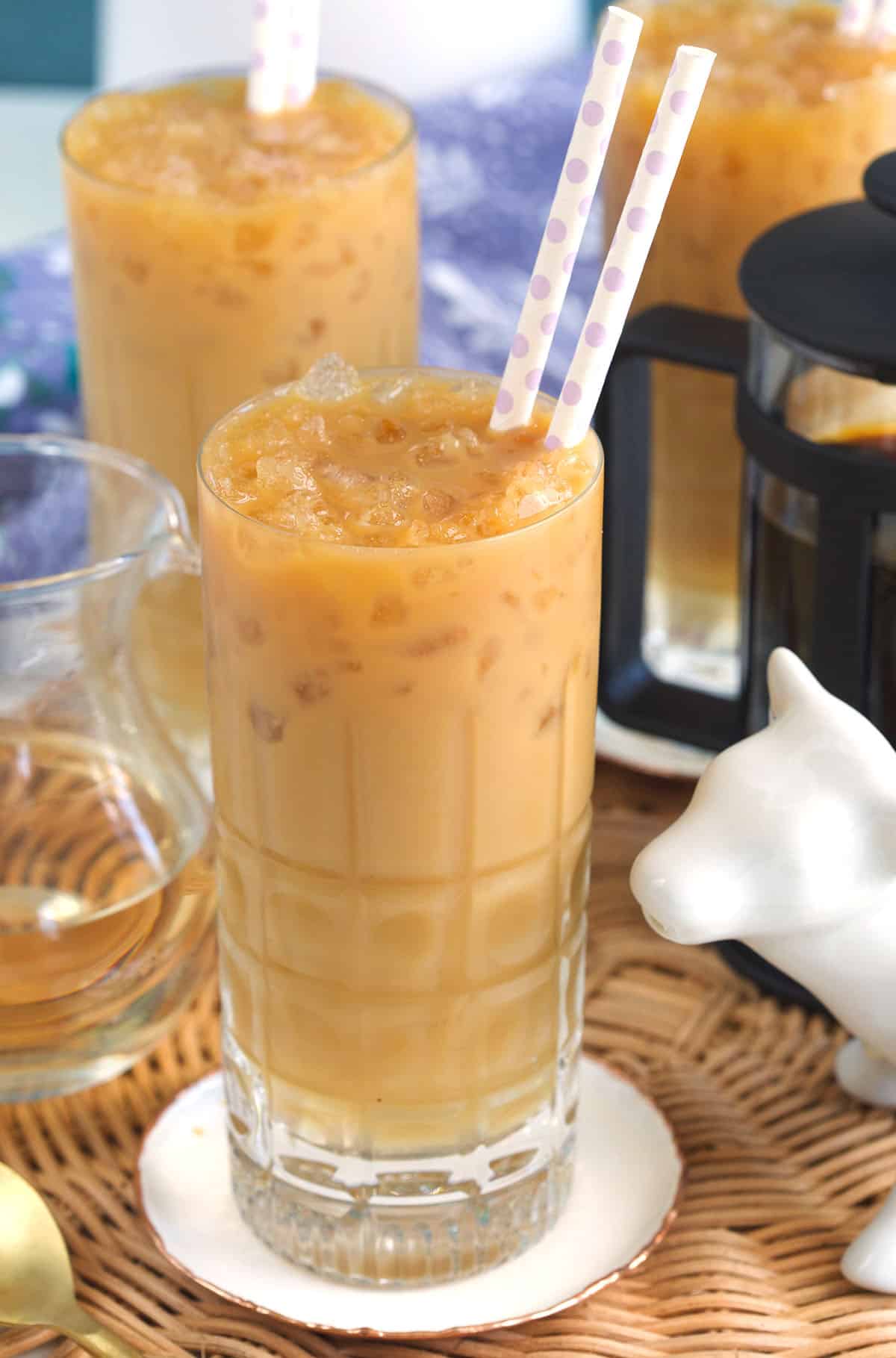 Two straws are placed in a glass cup filled with iced latte. 