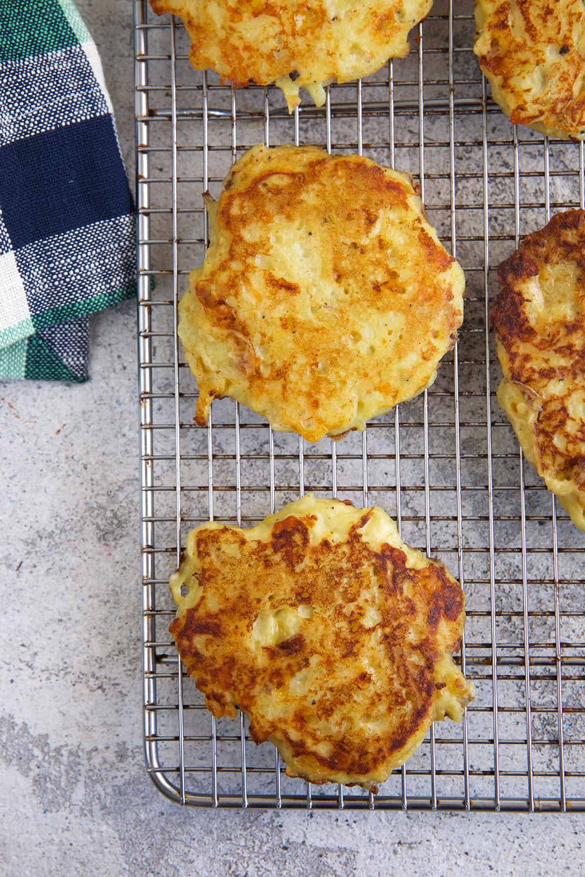 Several potato pancakes are placed on a wire cooling rack. 