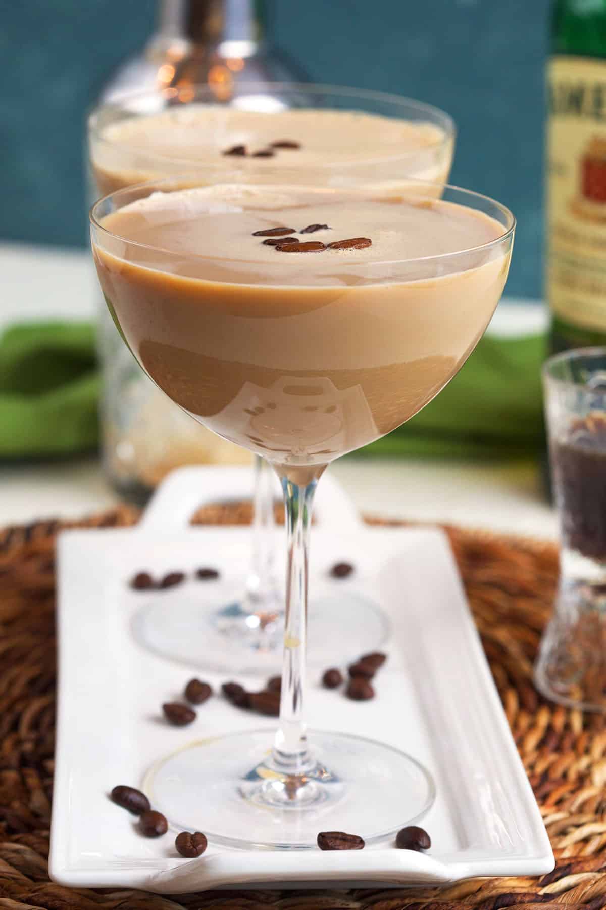 Several espresso martinis are placed on a white platter. 