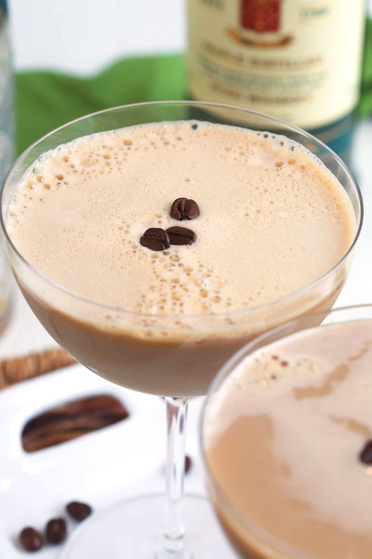Several coffee beans are placed on top of an espresso martini. 