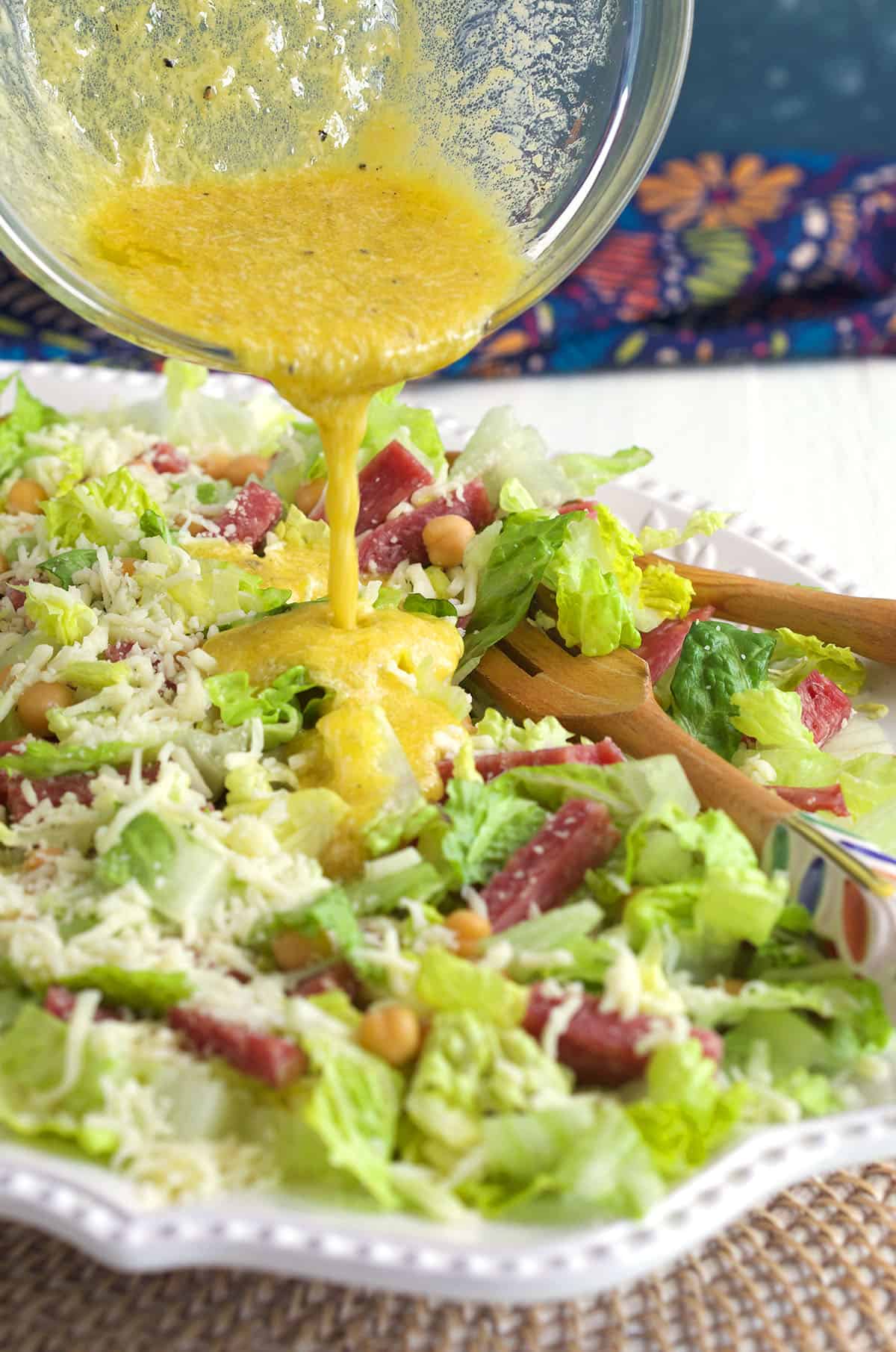 Dressing is being poured on top of a salad. 