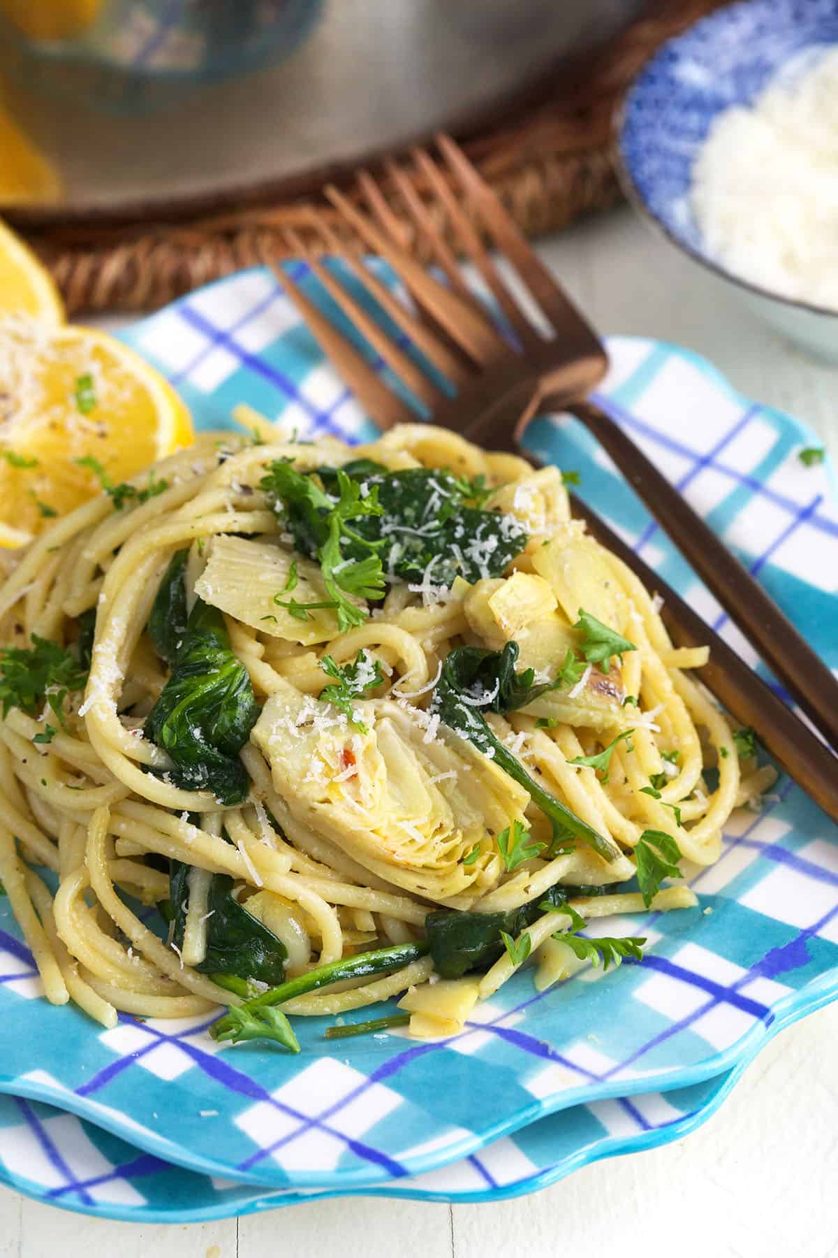 A single serving of lemon artichoke pasta is on a blue and white plate.