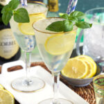Two glasses of limoncello spritz are on a white plate.
