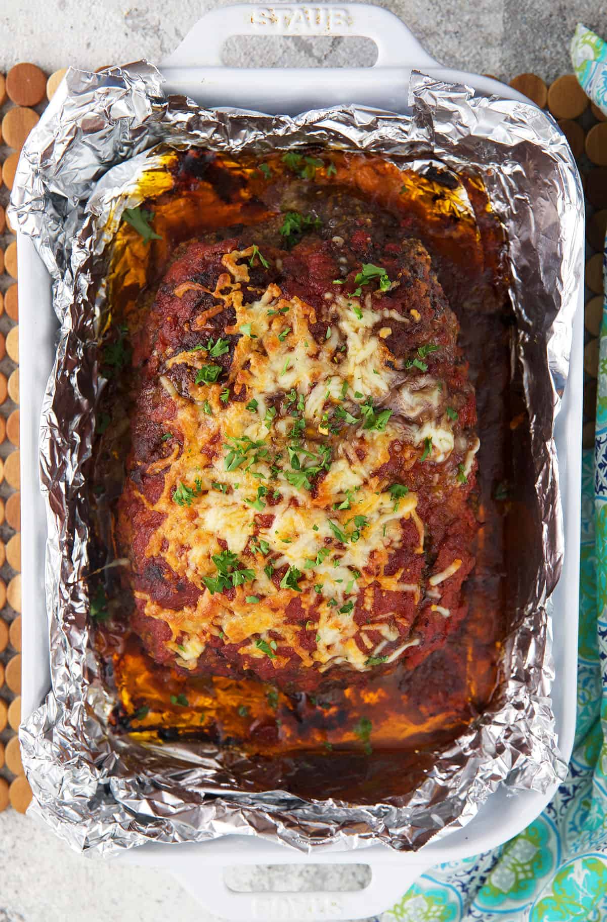 An Italian meatloaf is presented in a baking dish with foil. 