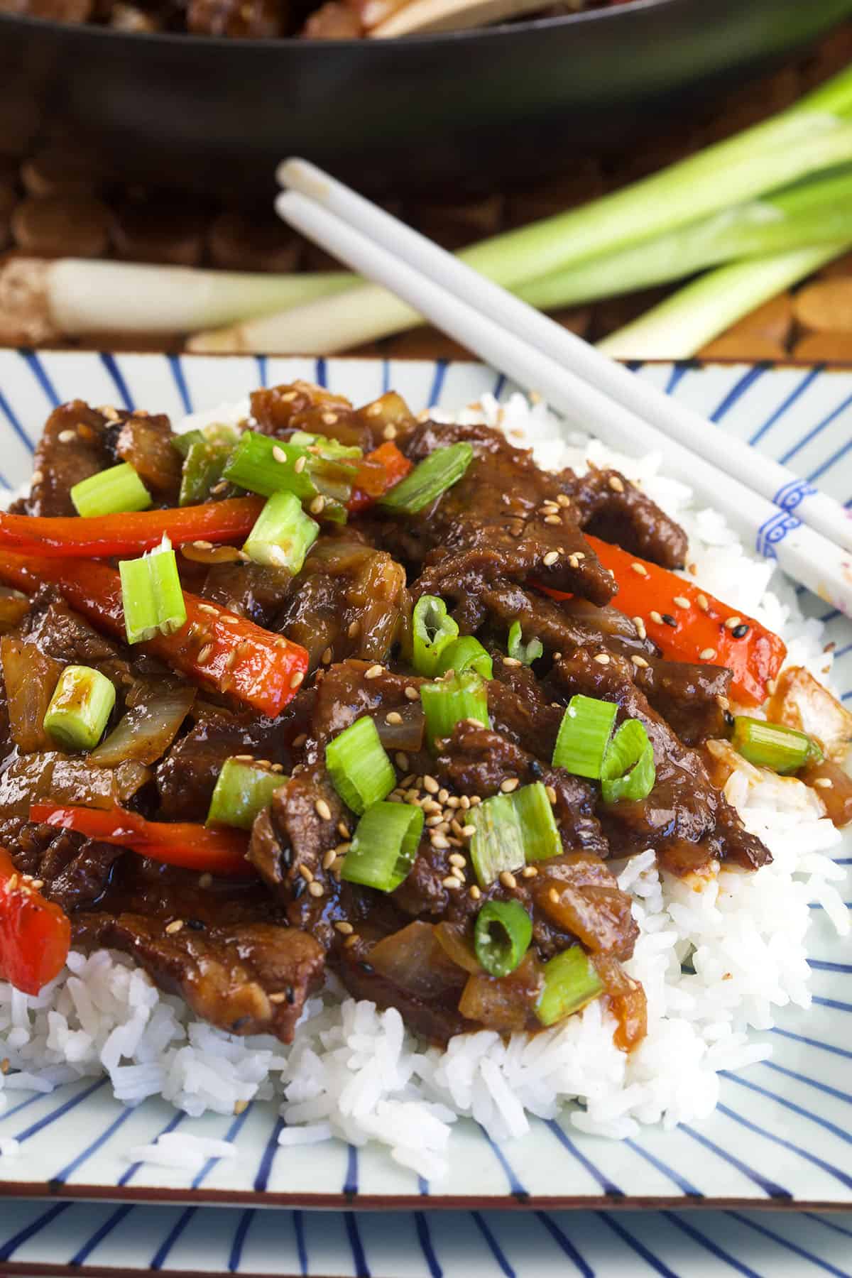 A serving of Beijing beef is placed on top of fluffy white rice.
