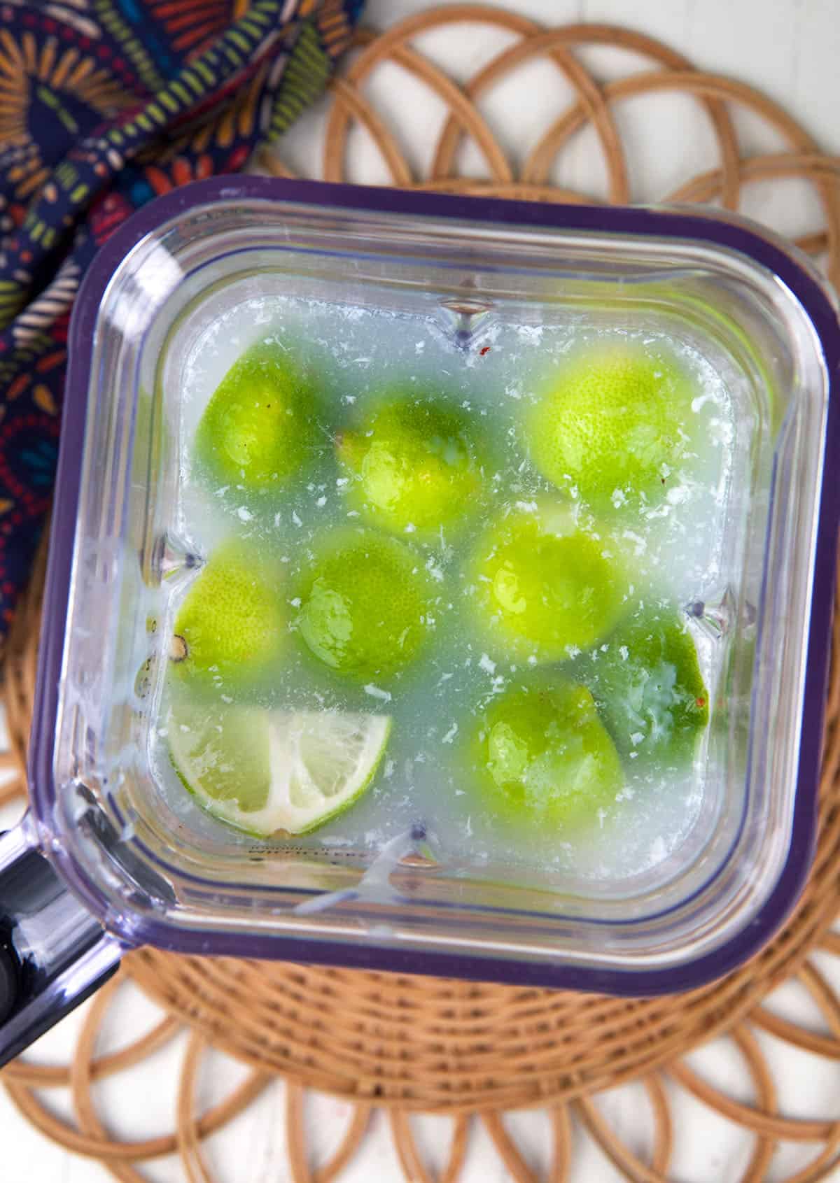 Limes and water are in a blender. 
