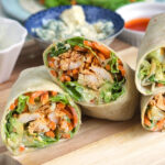 Buffalo Chicken Wrap cut in half and plated on a wooden board